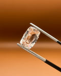 Natural 3.85ct imperial topaz, cushion cut, soft peach-gold, held in gemologist tweezers