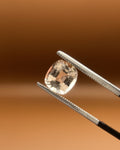 Natural 1.75ct imperial topaz, cushion cut, soft peach, held in gemologist tweezers